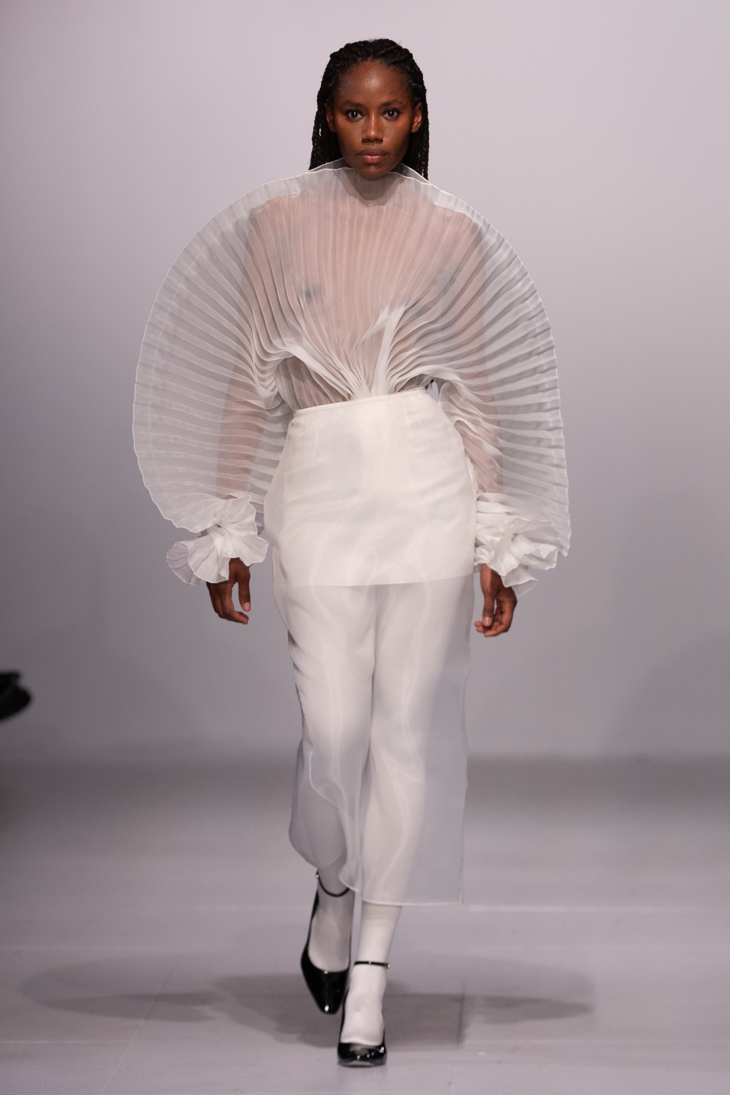 Fleur Set by J'amemme — model walking runway in white pleated bridal top and skirt set with dramatic sculptural sleeves