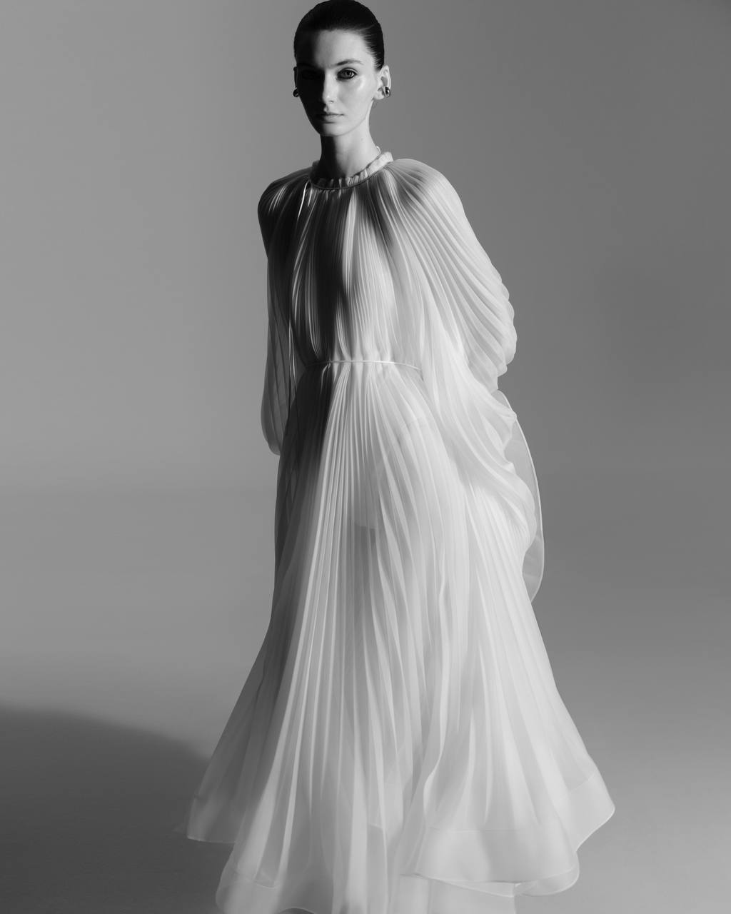 Virgin Dress by J'amemme — model wearing white pleated bridal gown, full-length editorial studio portrait