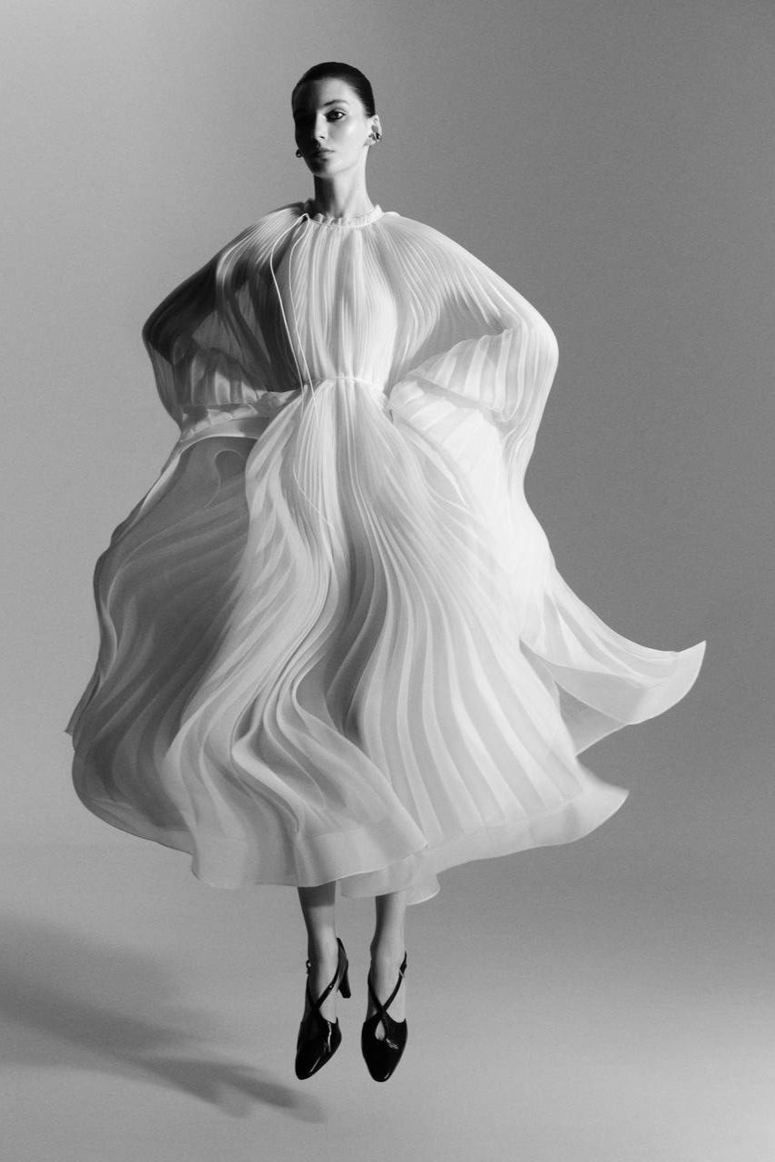 Virgin Dress by J'amemme — model in white pleated bridal gown captured in movement, editorial studio shot