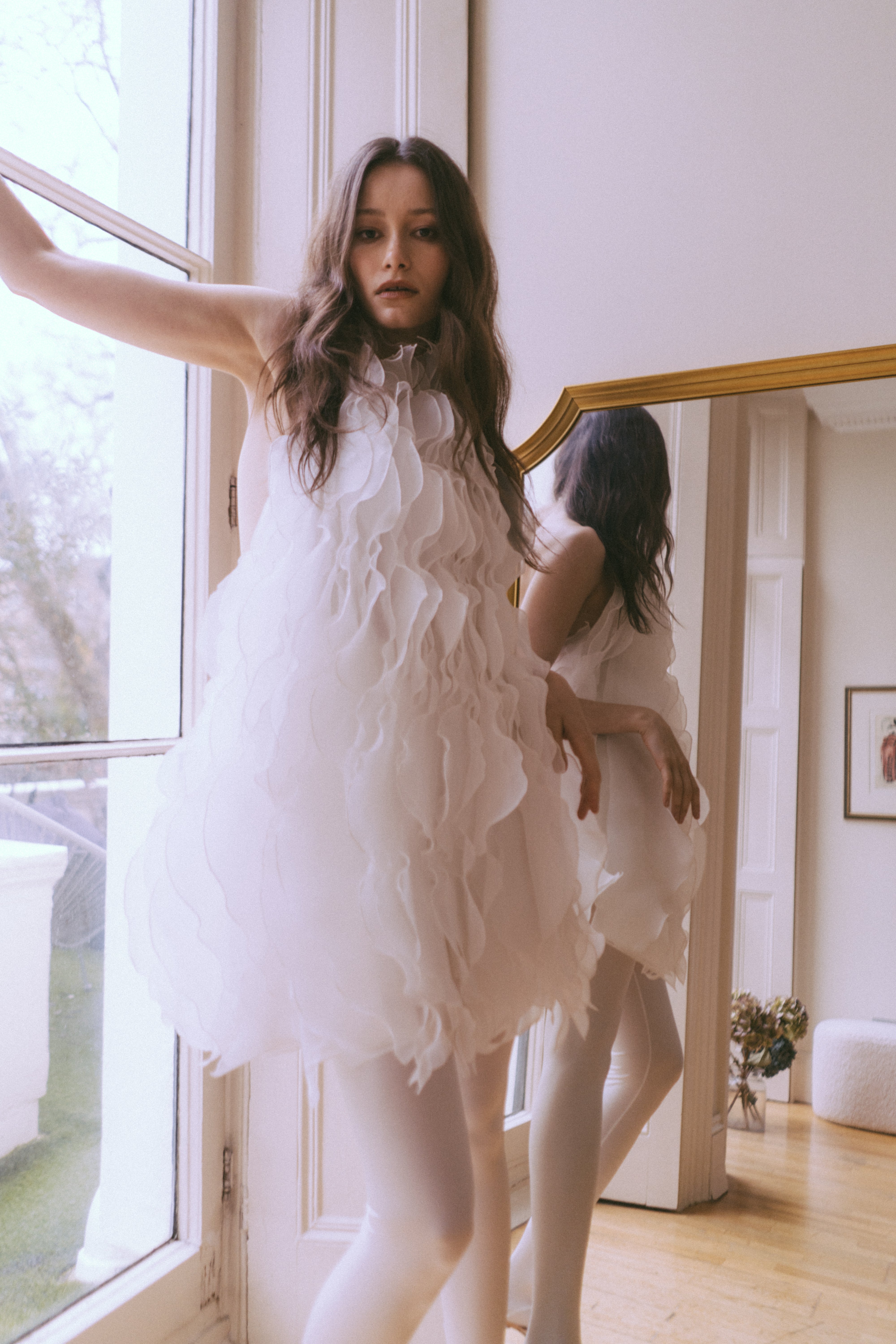 Wave White Dress by J'amemme — editorial lookbook shot of model in ruffled bridal mini dress by window