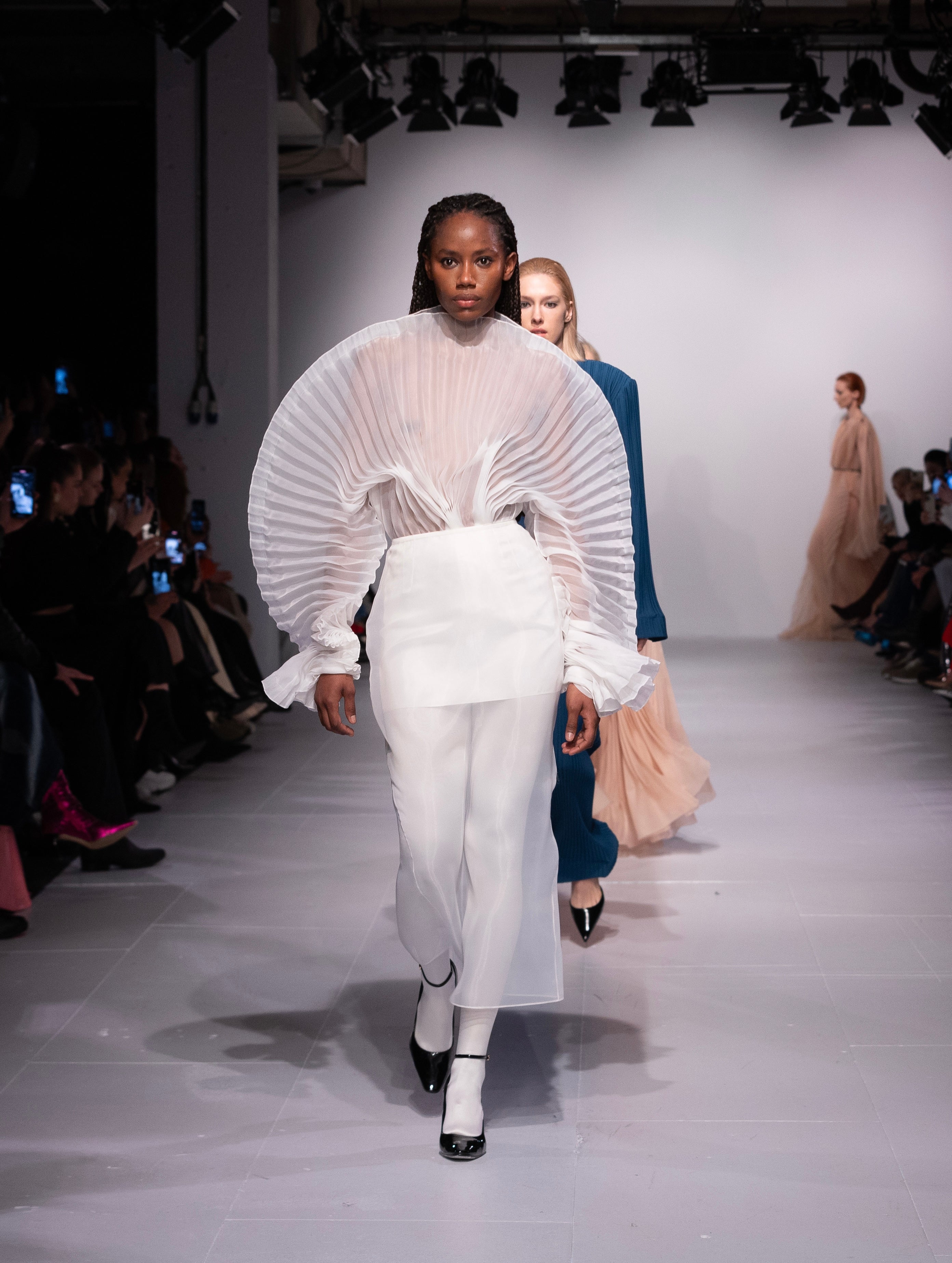 Fleur Set by J'amemme — model in white pleated bridal top and skirt on runway finale with other models in background