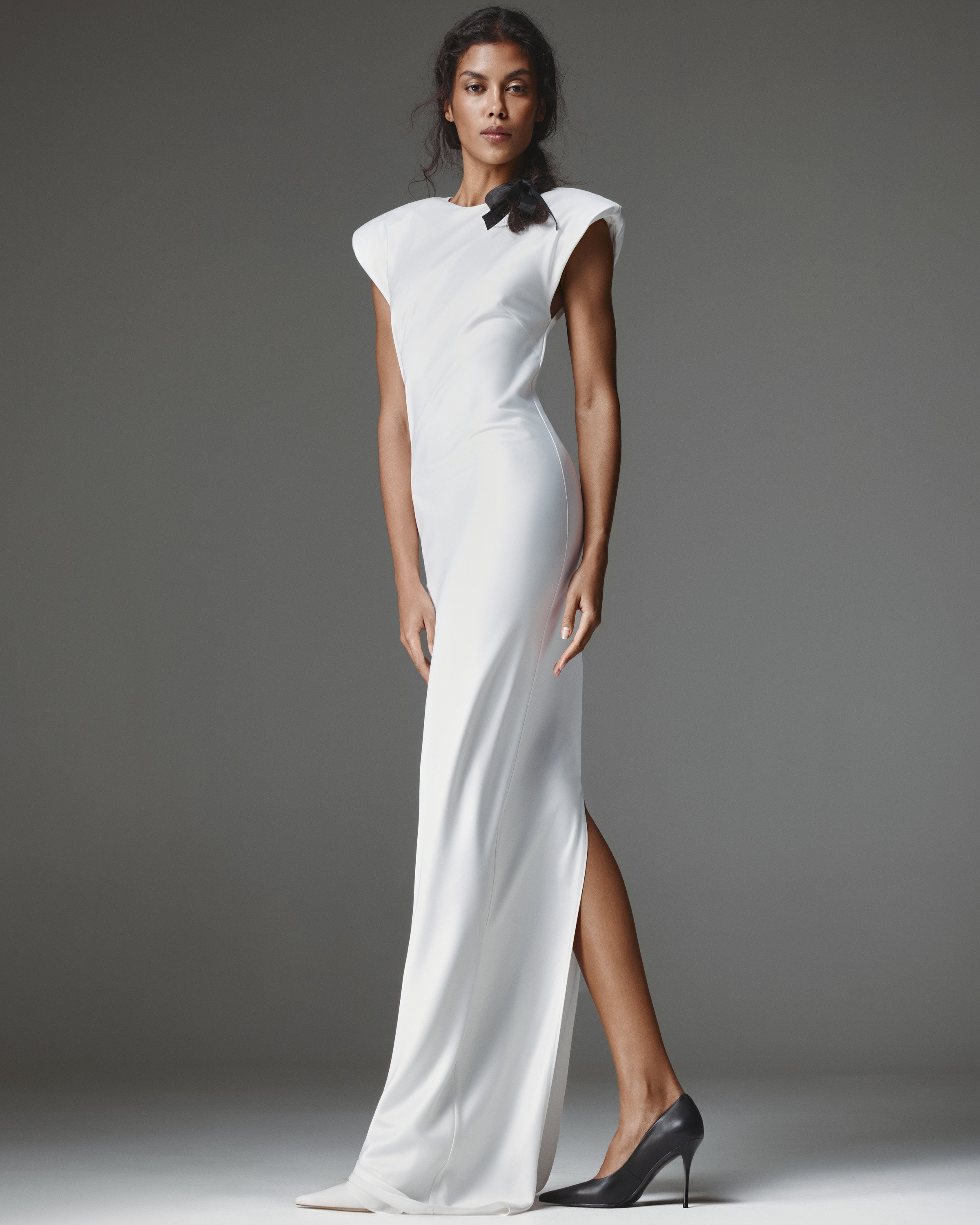 Clemence Dress by J'amemme — front view, white column gown with square cap-sleeve shoulders, black ribbon bow neckline and side slit