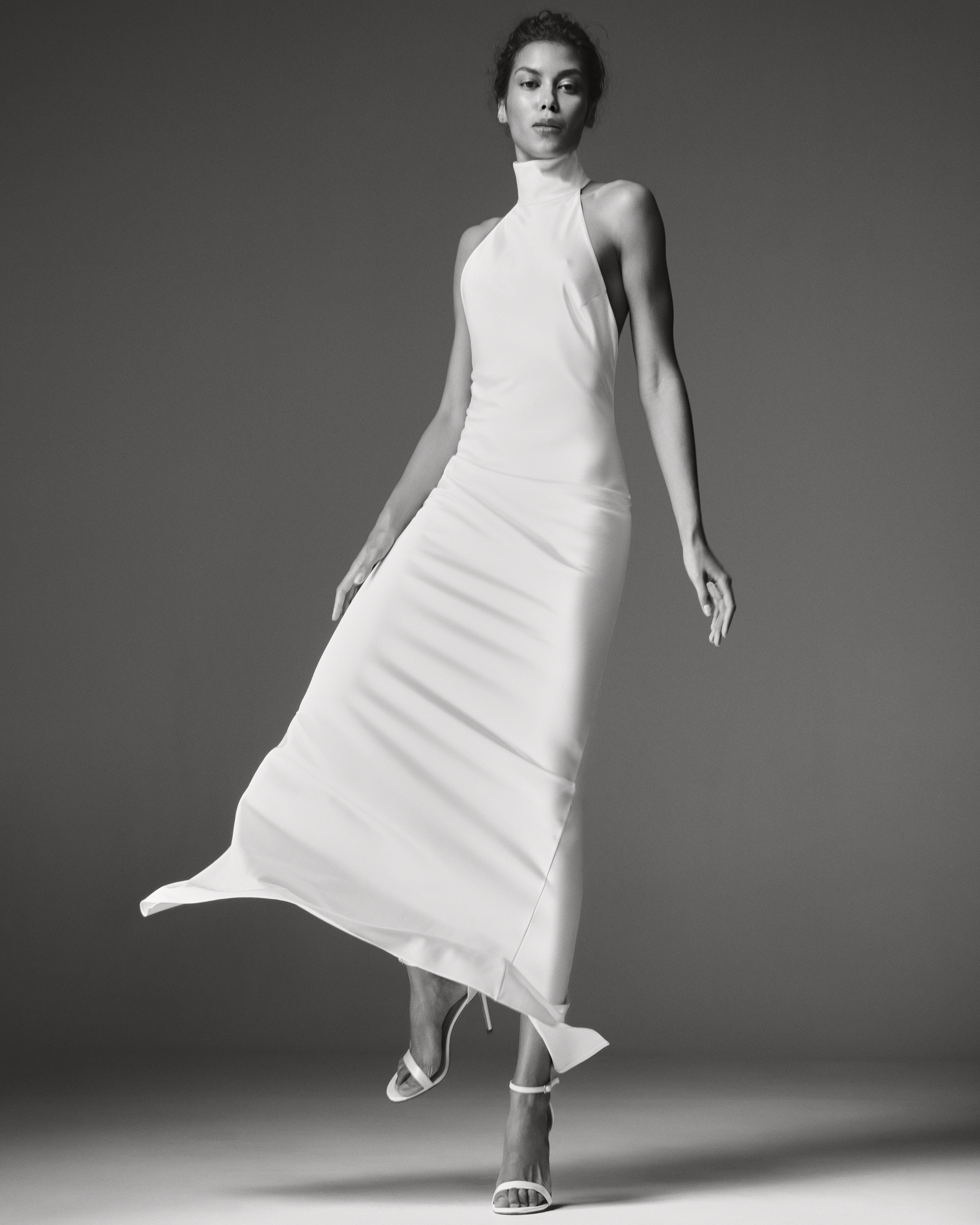 Devon Dress by J'amemme — white satin halter-neck wedding gown, sleeveless floor-length silhouette, black-and-white editorial front view.