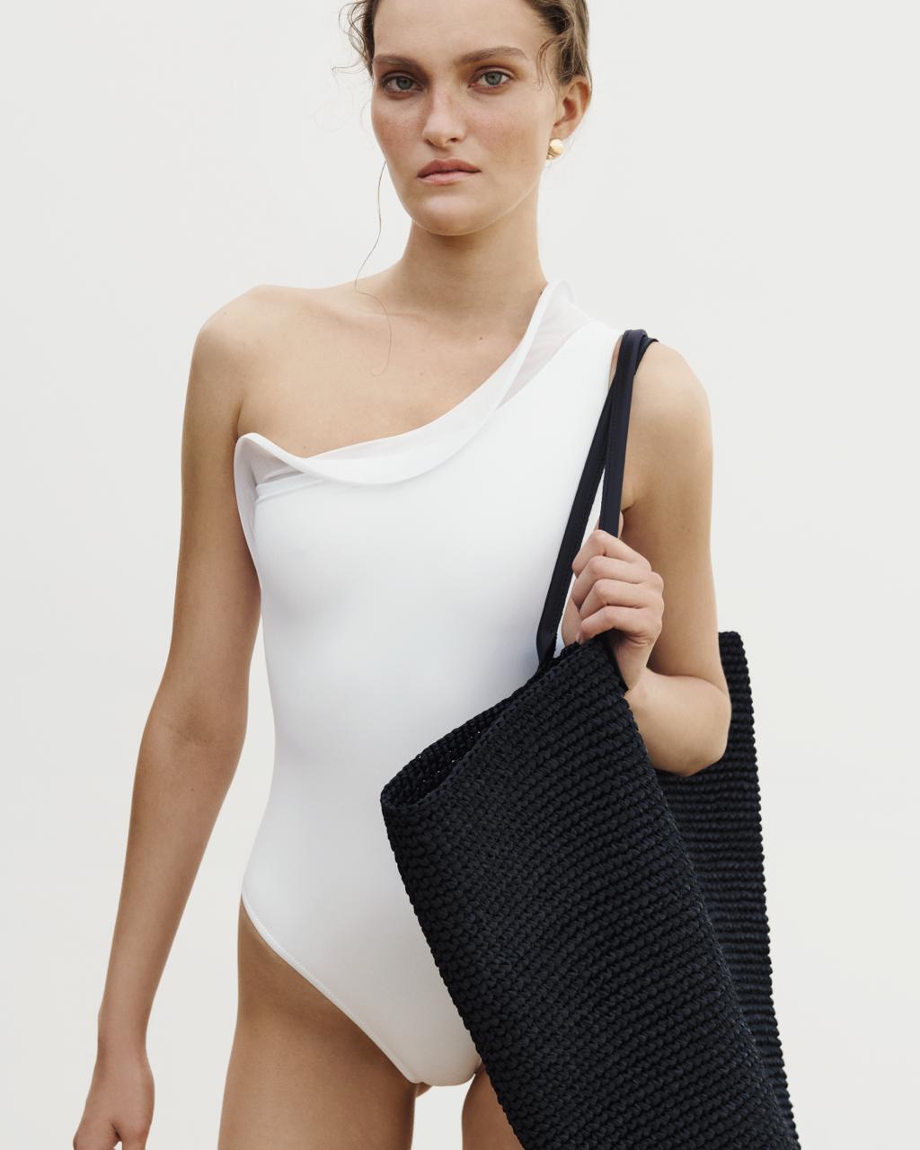 Detail of the sculpted wave inset on the white Thelxie one-shoulder swimsuit, J'AMEMME Resort '27